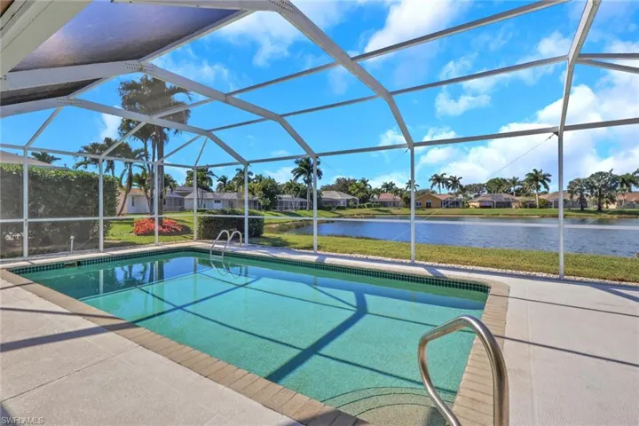 Outdoor pool with glass enclosure, a sunroom, a water view, and a residential view