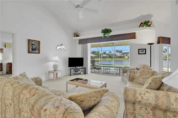 Carpeted living area with high vaulted ceiling and ceiling fan