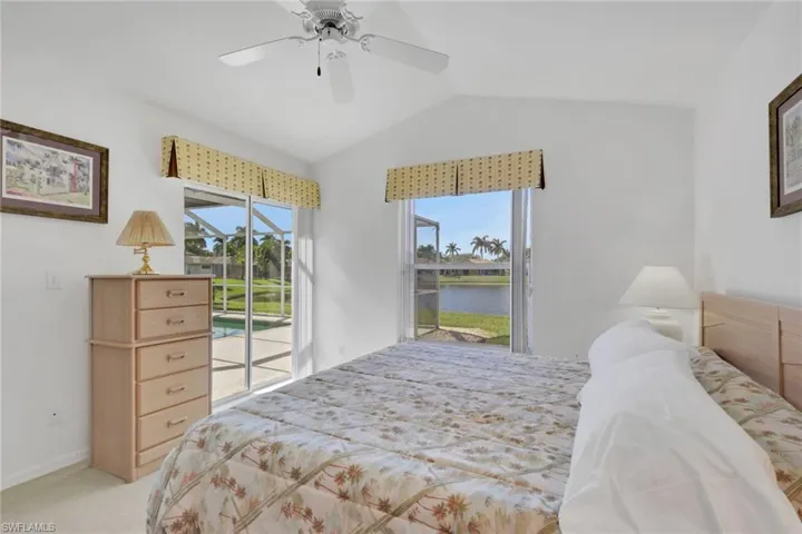 Bedroom featuring access to exterior, a water view, carpet floors, ceiling fan, and vaulted ceiling