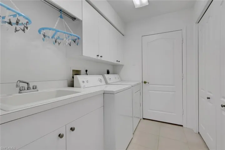 Laundry area featuring cabinet space, light tile patterned floors, and washer and clothes dryer