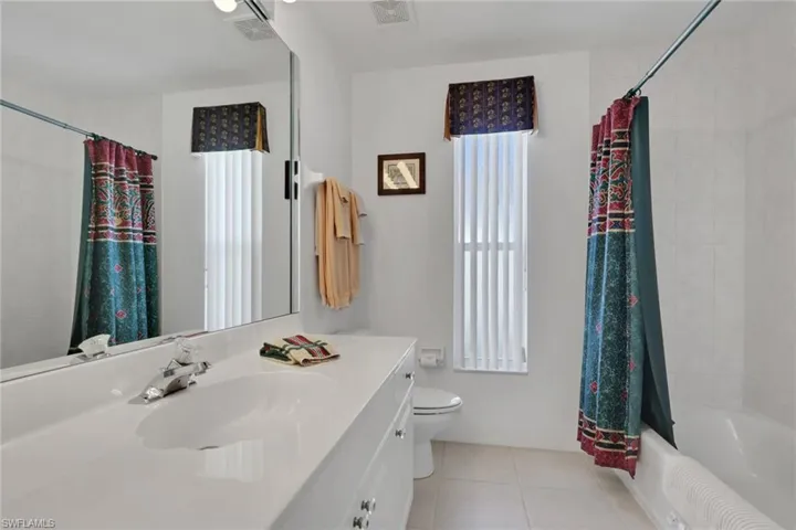 Full bath featuring vanity, shower / bathtub combination with curtain, and light tile patterned floors
