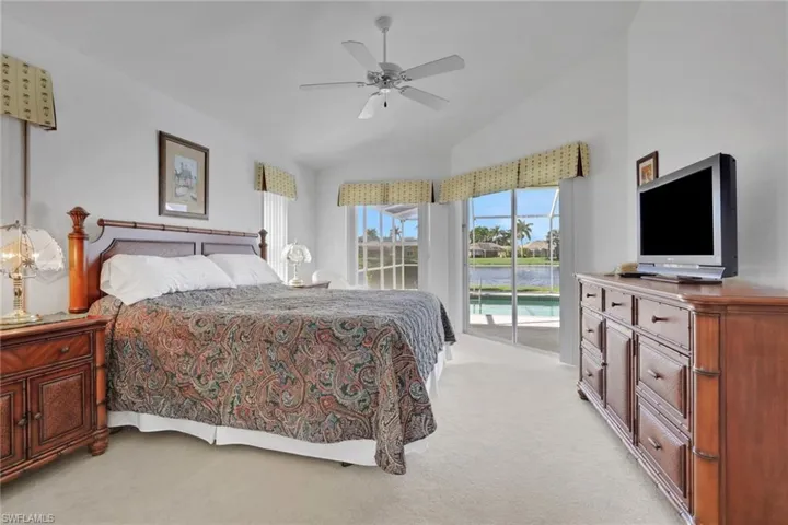 Bedroom featuring access to exterior, light carpet, lofted ceiling, and ceiling fan