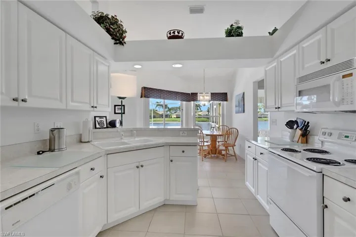 Kitchen featuring white appliances, white cabinetry, light countertops, light tile patterned floors, and recessed lighting