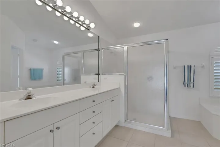Full bathroom with double vanity, a garden tub, a stall shower, and light tile patterned floors