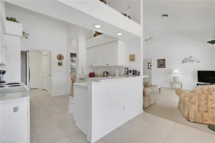 Kitchen with a towering ceiling, white cabinetry, light countertops, open floor plan, and light tile patterned floors
