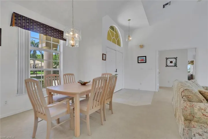 Dining space with light carpet, a high ceiling, and a chandelier