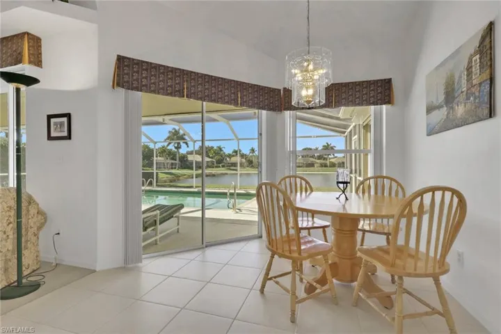 Dining room featuring a sunroom, a water view, light tile patterned floors, and a chandelier