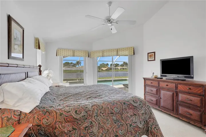 Bedroom with light carpet, access to exterior, vaulted ceiling, and ceiling fan