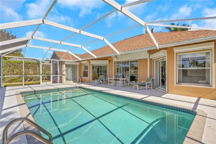 Outdoor pool with glass enclosure, a sunroom, and a patio