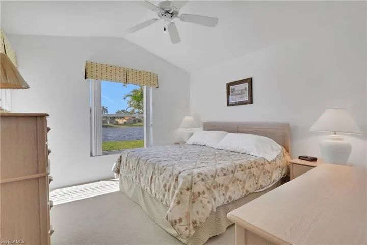 Bedroom with a water view, lofted ceiling, a ceiling fan, and carpet floors
