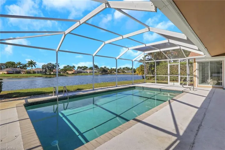Outdoor pool featuring glass enclosure, a patio area, a sunroom, and a water view