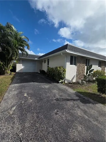 Single story home with stucco siding, a garage, asphalt driveway, and roof with shingles
