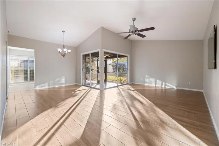 Unfurnished room with wood tiled floors, a ceiling fan, a chandelier, and lofted ceiling