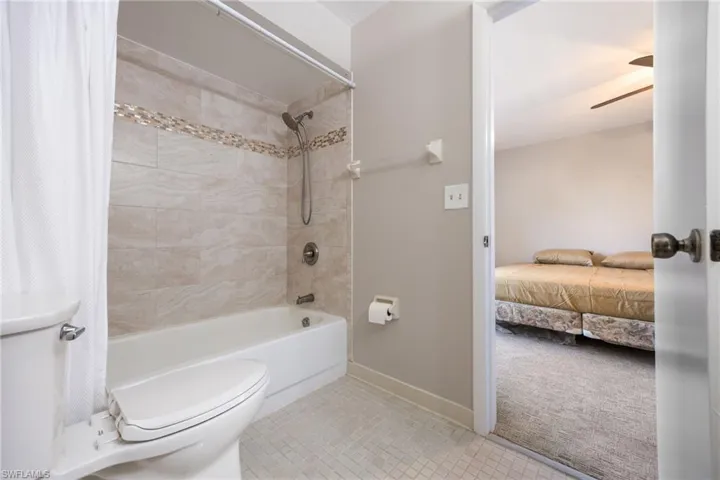 Bathroom with shower / bath combo with shower curtain, light tile patterned floors, light colored carpet, connected bathroom, and a ceiling fan