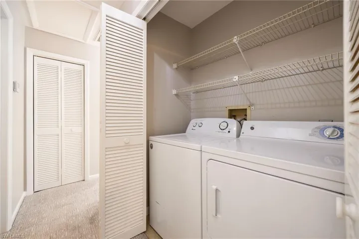 Laundry area featuring light colored carpet and washing machine and dryer