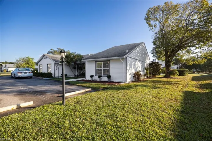 Ranch-style home with a front yard, uncovered parking, and roof with shingles