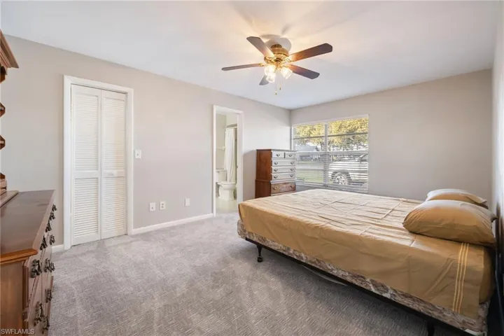 Carpeted bedroom featuring a ceiling fan and ensuite bath