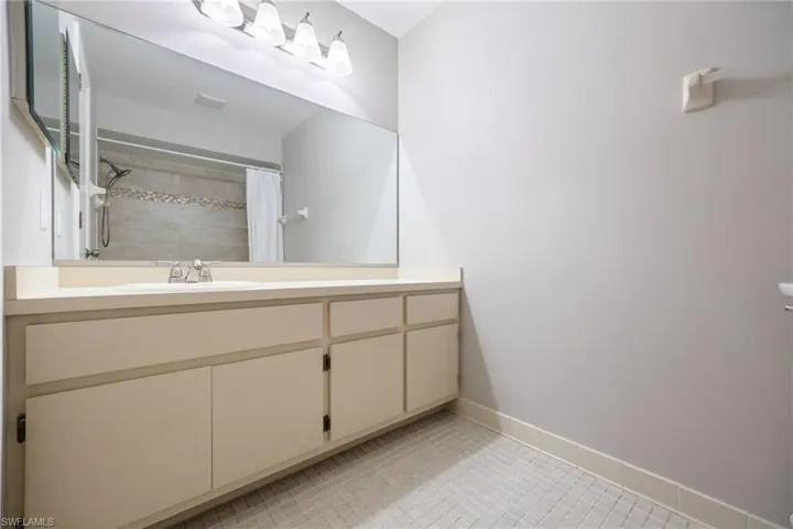Full bathroom featuring vanity, a tile shower, and light tile patterned floors