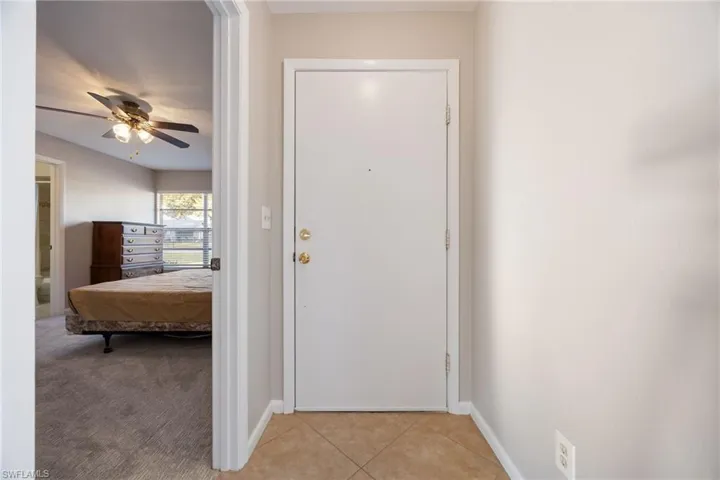 Entryway featuring a ceiling fan, tile patterned flooring, and carpet