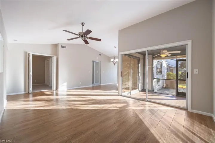 Spare room with ceiling fan, wood tiled floors, a chandelier, and lofted ceiling