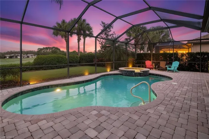 Pool at dusk featuring a sunroom, a pool with connected hot tub, a lanai, and a patio