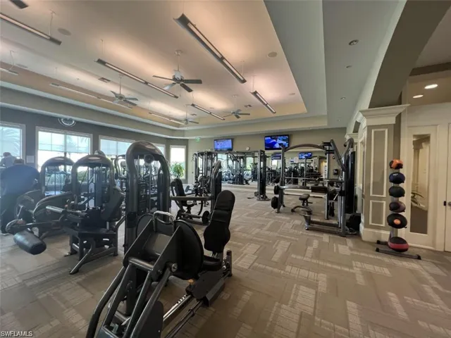 Exercise room featuring a ceiling fan and a raised ceiling