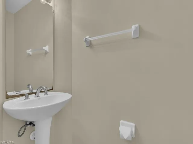 Powder room with a decorative mirror above a classic pedestal sink.