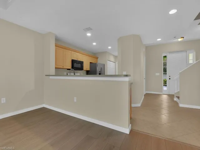 Detailed view showcasing the kitchen from the perspective of the living room, highlighting modern recessed lighting fixtures and the elegant installation of tile flooring throughout the space.
