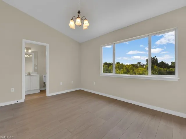 Spacious primary bedroom and ensuite bathroom featuring an abundance of natural light streaming in, complemented by a stunning vaulted ceiling design and durable, elegant LVP (Luxury Vinyl Plank) flooring throughout.