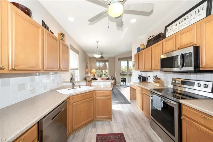 Kitchen featuring stainless steel appliances, light countertops, a peninsula, ceiling fan, and hanging light fixtures