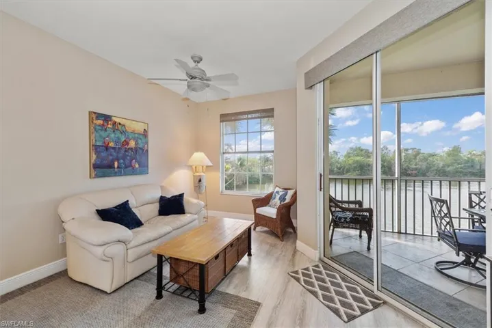 Living room featuring light wood-style flooring, ceiling fan, and a water view