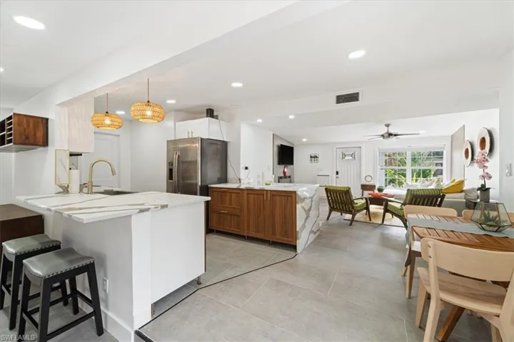 Kitchen with kitchen peninsula, stainless steel fridge, ceiling fan, sink, and hanging light fixtures