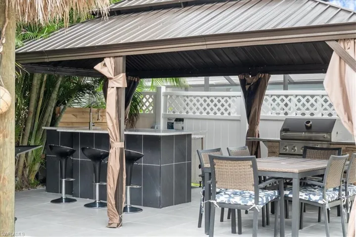 View of patio with exterior bar, a gazebo, an outdoor kitchen, and a grill