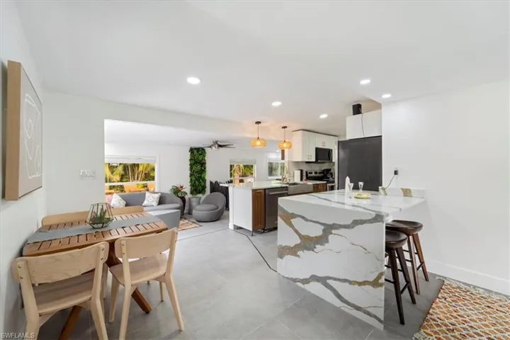 Kitchen featuring pendant lighting, a breakfast bar, white cabinets, appliances with stainless steel finishes, and kitchen peninsula