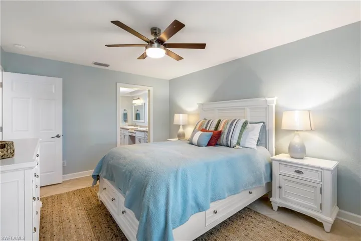 Bedroom featuring light tile patterned flooring, a ceiling fan, and connected bathroom