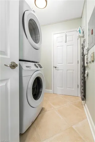 Washroom featuring stacked washing machine and dryer and light tile patterned floors
