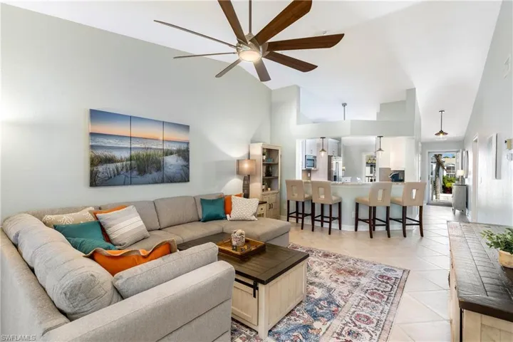 Living room with ceiling fan, high vaulted ceiling, and light tile patterned flooring
