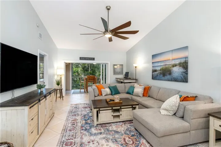 Living room featuring high vaulted ceiling, ceiling fan, and light tile patterned flooring