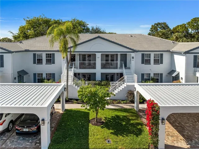 Back of property featuring stucco siding, stairway, a tiled roof, and a lawn