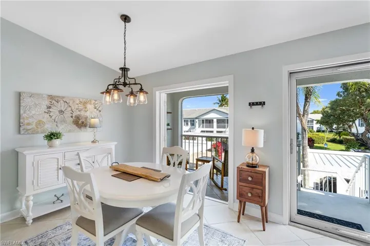 Tiled dining area with lofted ceiling and a chandelier