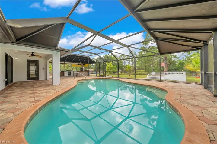 Swimming pool featuring a patio, a sunroom, ceiling fan, and a lanai