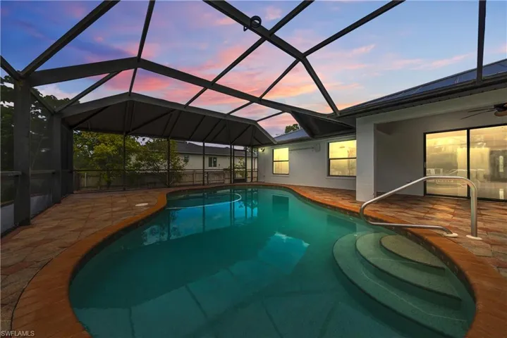 Swimming pool with a sunroom, glass enclosure, a ceiling fan, and a patio area
