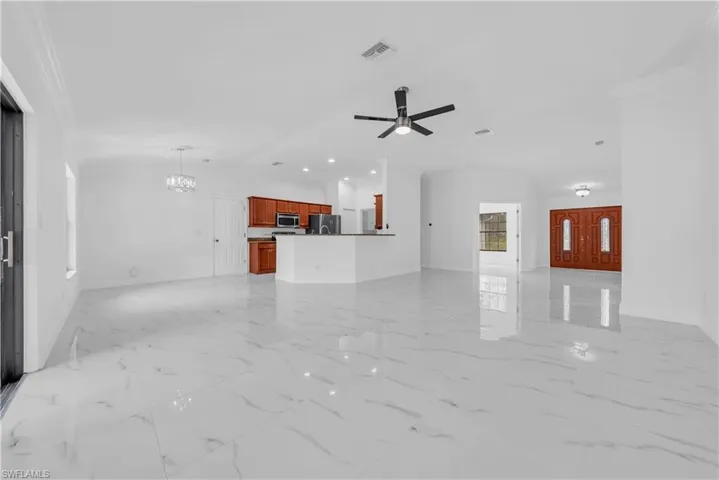 Unfurnished living room featuring light marble finish floors, lofted ceiling, a chandelier, ceiling fan, and recessed lighting