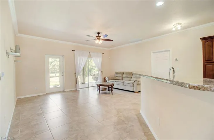 Tiled living room featuring crown molding, sink, and ceiling fan
