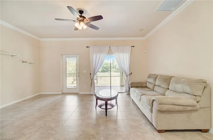 Living room with ceiling fan, tile floors, and crown molding