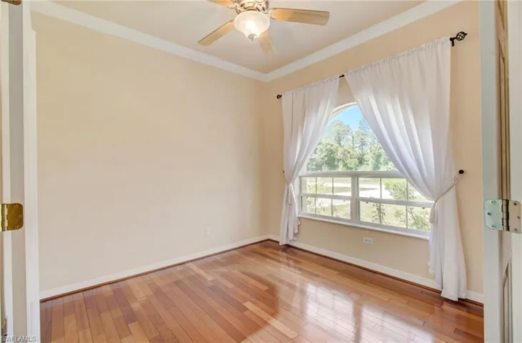 Spare room featuring ceiling fan, crown molding, and wood-type flooring