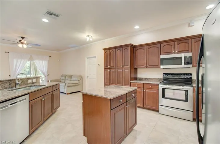 Kitchen with light tile flooring, ceiling fan, a center island, appliances with stainless steel finishes, and sink