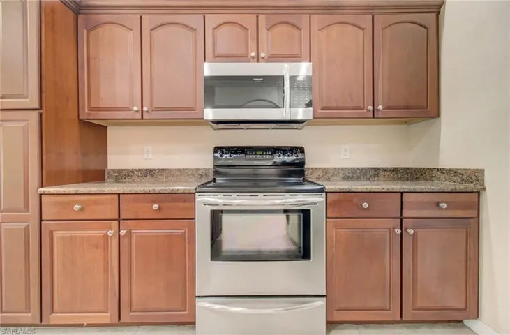 Kitchen with stainless steel appliances, light tile flooring, and stone countertops