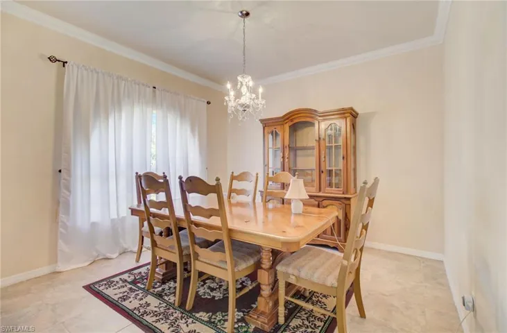 Dining space featuring a notable chandelier, ornamental molding, and light tile flooring