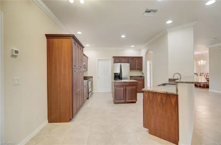 Kitchen featuring stainless steel appliances, crown molding, sink, and light tile floors